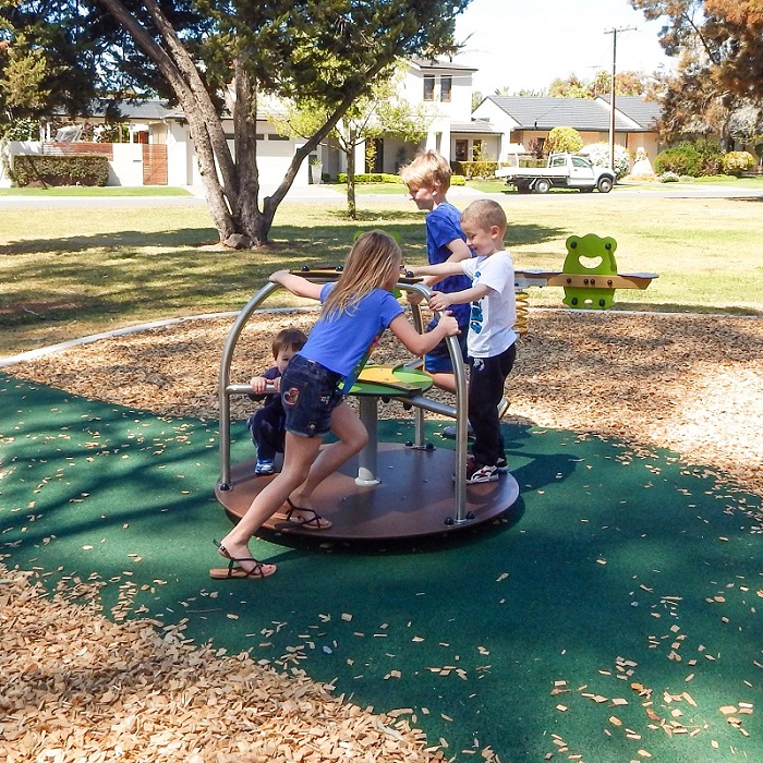Child playing on a carousel at Cummins Reserve Playground