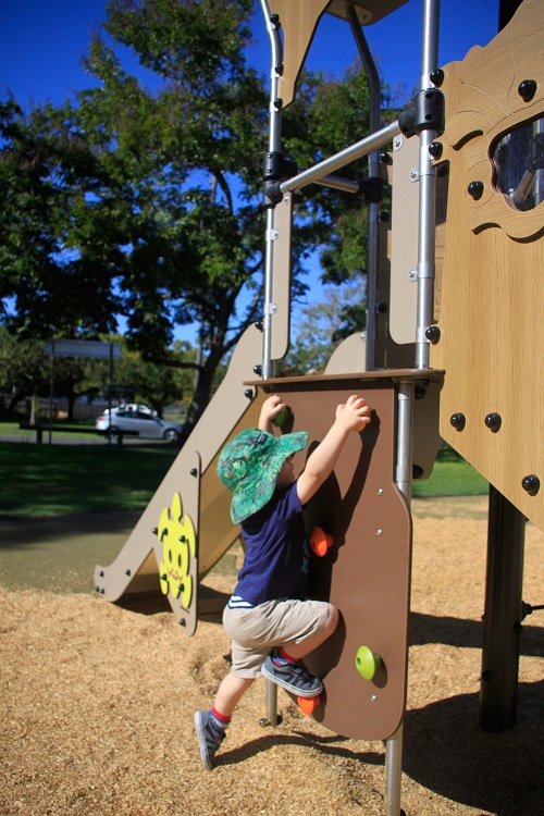 Child playing on a climbing wall at Joe Foster Park playground
