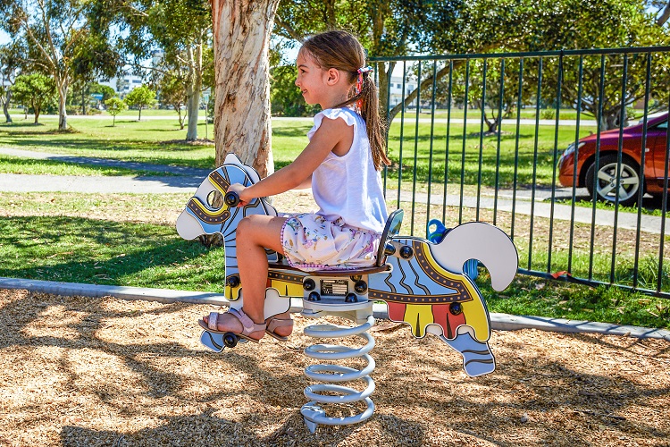 Child playing on a horse springer ta Tugun Park castle themed playground