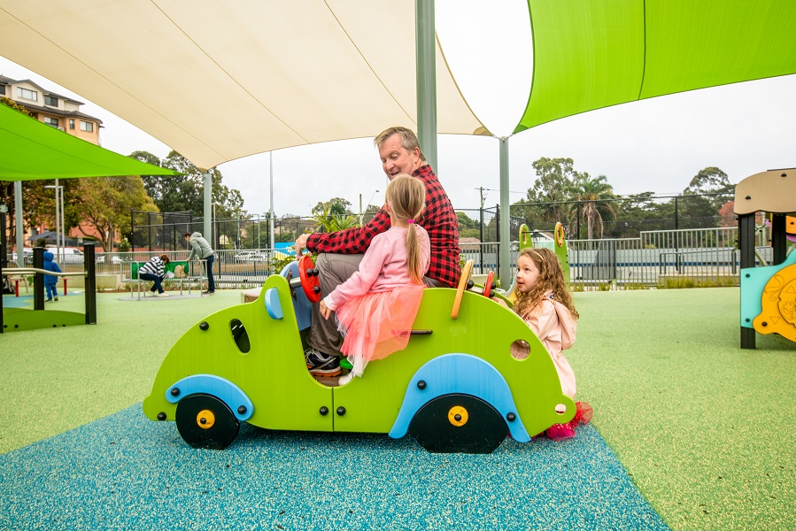Child playing on a car at Waitara Park Inclusive Playspace