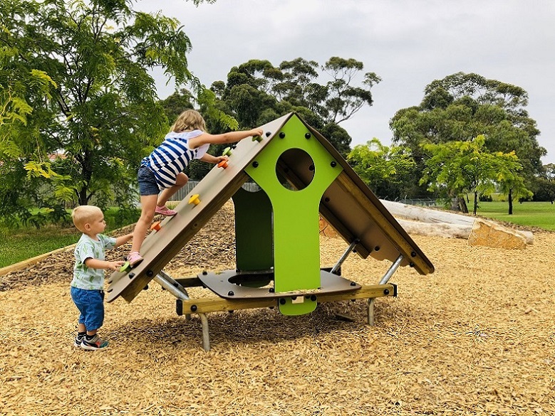 Chils playing on a playhouse at Nature-inspired Kanopé Multi-Play unit