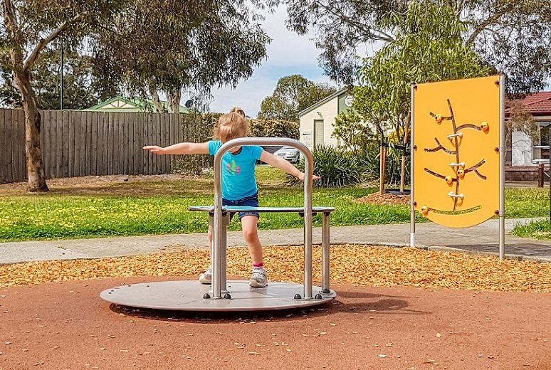 Child playing on a carousel at Tranter Square Reserve Playground