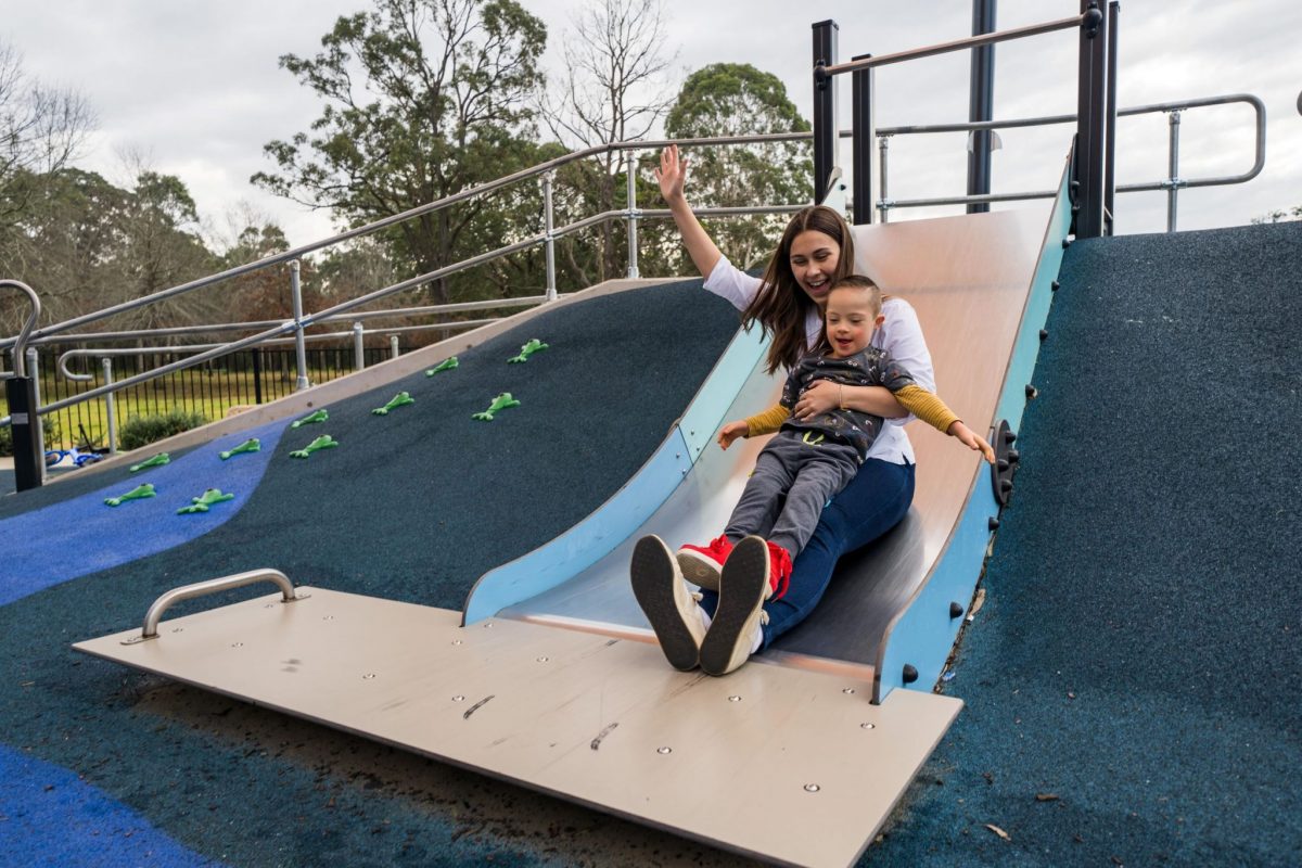 Adult and child with down syndrome going down a slide