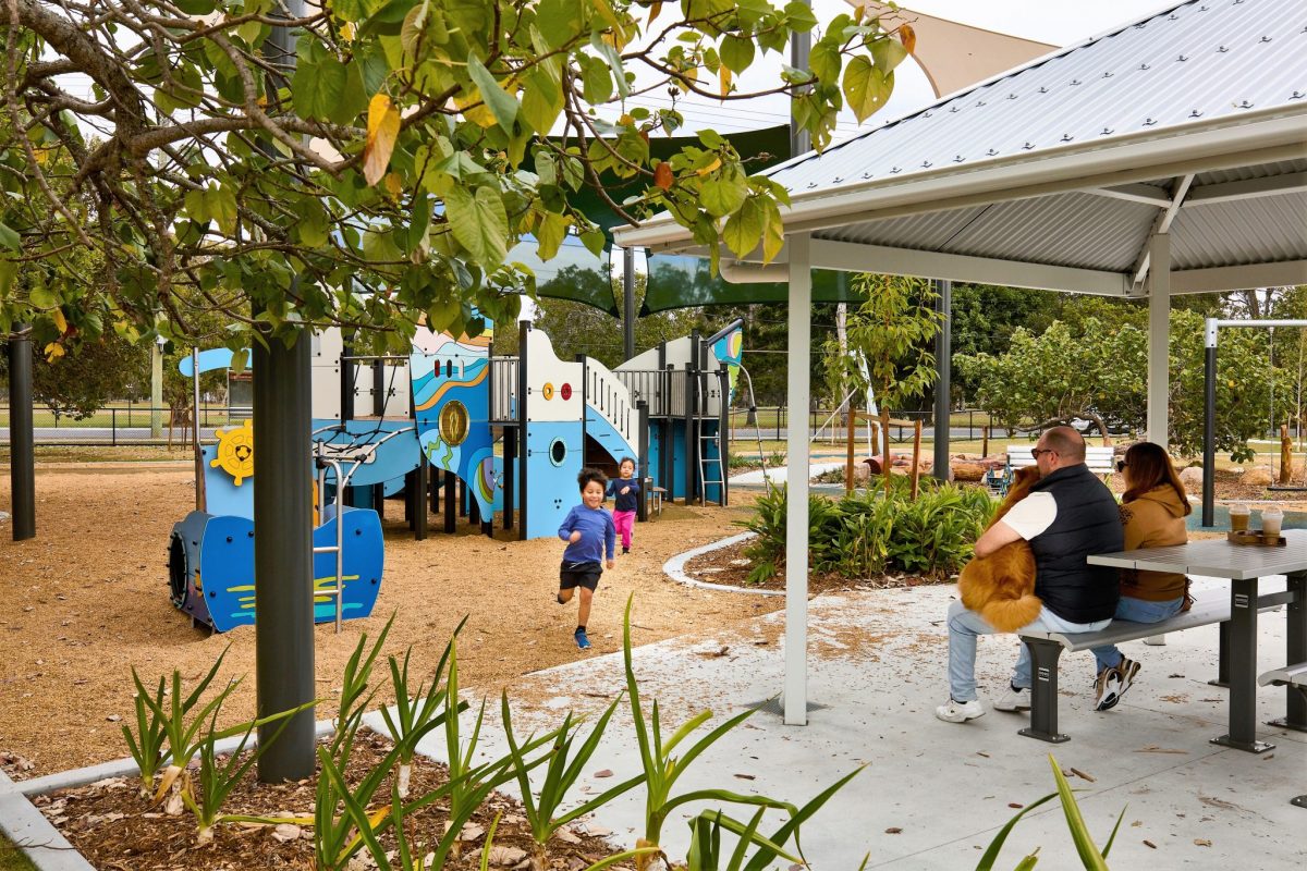People watching their children from covered Picnic Area at playground