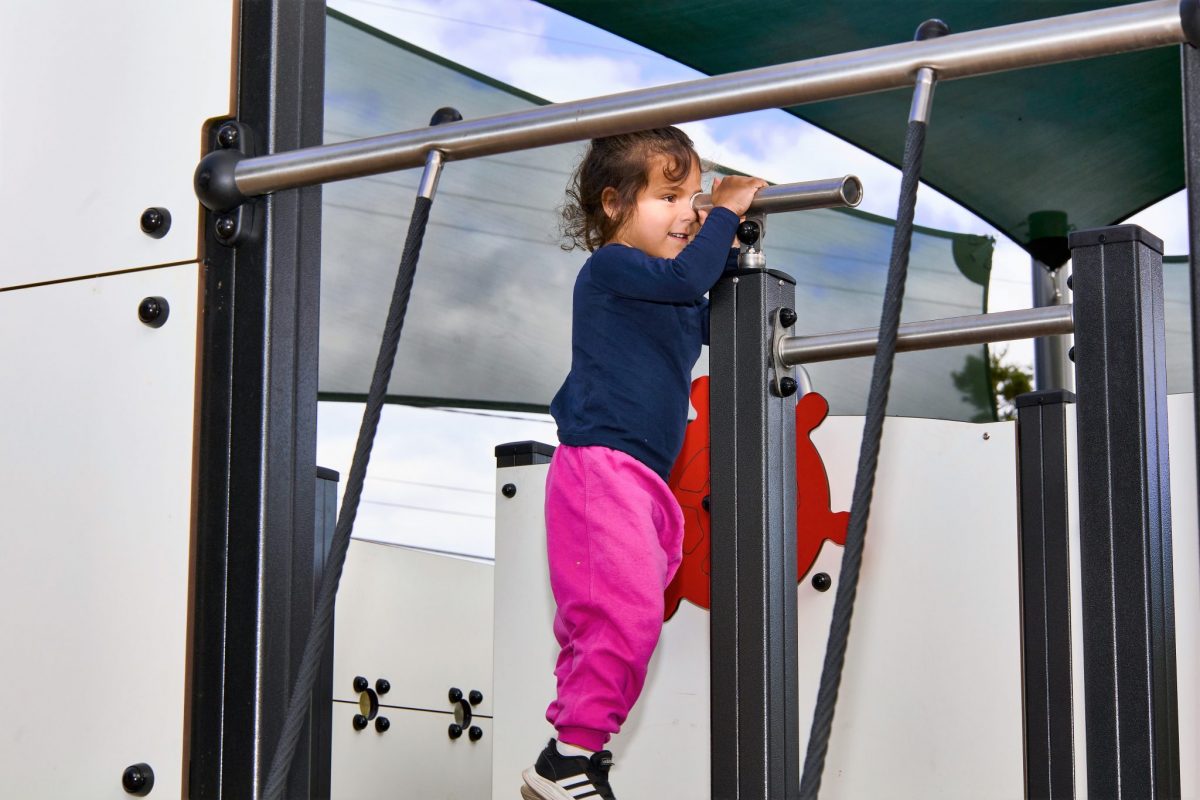Child looking through telescope on play structure