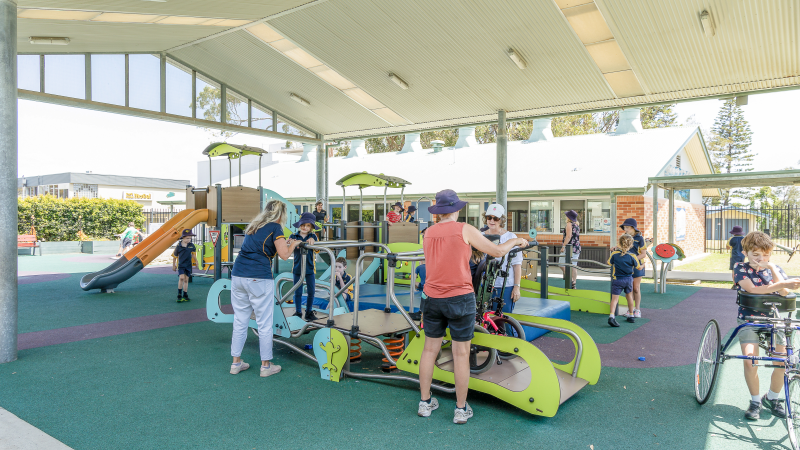 Children and carers playing with inclusive seasaw