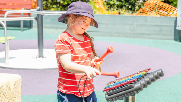 Child with down syndrome playing with outdoor musical instrument at Port Macquarie Public School Inclusive Playground