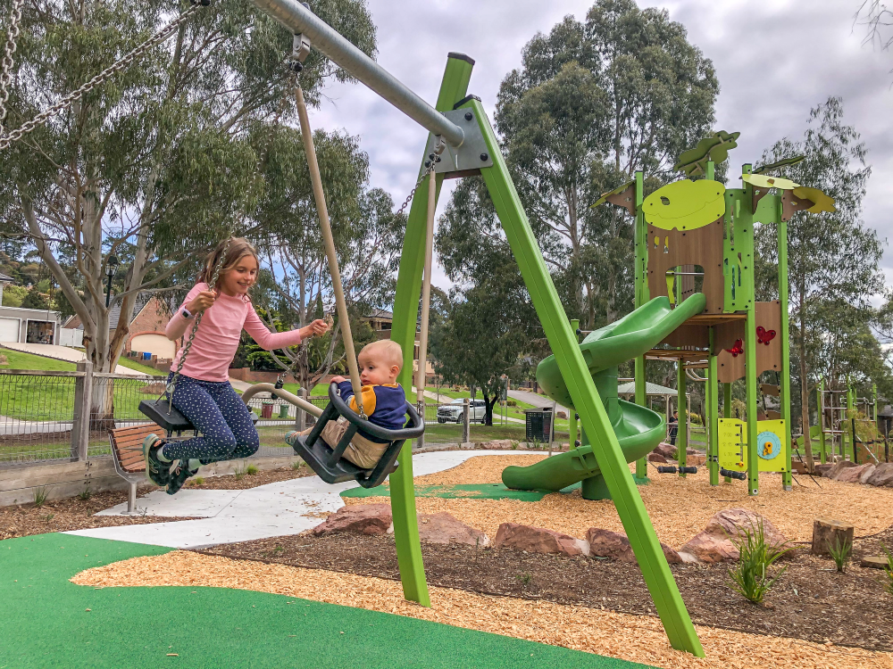 Children swinging facing each other on duo swing