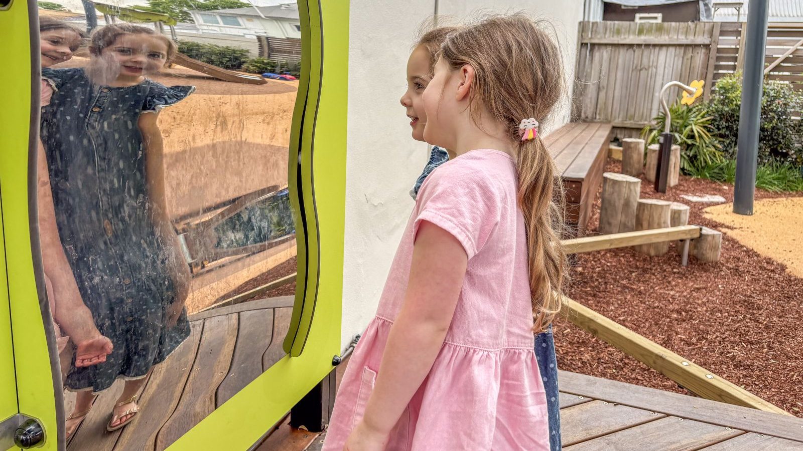 Twin girls looking into Wobbly Mirror at Spring Street Reserve Toddler Playground